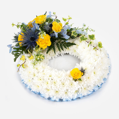 Wreath SYM-319 - White Massed Wreath with Blue & Yellow Spray. 